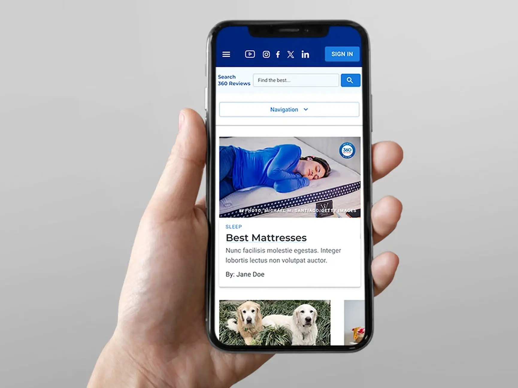 A hand holding a phone showing the redesigned mobile homepage, with the search field, the Navigation control, and the featured Best Mattresses card in the first viewport.